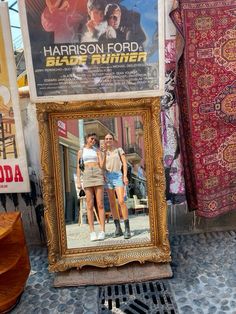 an old framed movie poster on display in front of a store window with other items