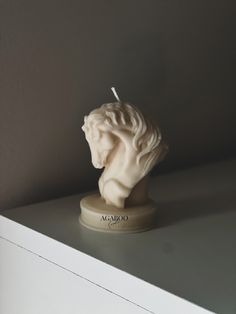 a small white candle sitting on top of a shelf