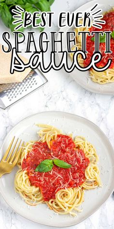 two plates of spaghetti with sauce and basil on the side, next to a knife and fork