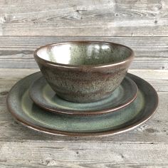 two bowls and one plate on a wooden table top with wood planks in the background