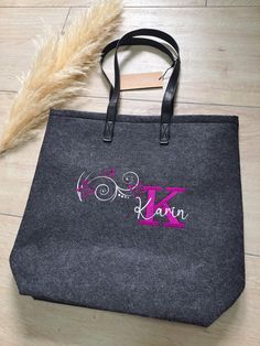 a black bag with pink letters and a feather on the floor in front of it