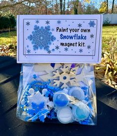 a snowflake magnet kit is sitting on a table in front of some trees