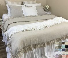 a bed with white ruffled bedspread, pillows and blankets on top of it