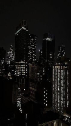 the city skyline is lit up at night, with skyscrapers in the foreground