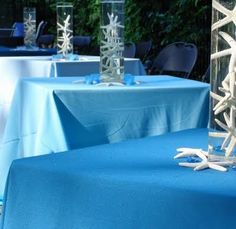 the table cloth is blue with white snowflakes on it and two clear vases filled with water