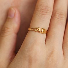 a woman's hand wearing a gold ring with the letter a on it and an arrow in the middle