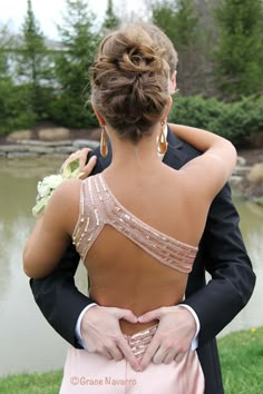 a man in a tuxedo hugging a woman with her back to the camera