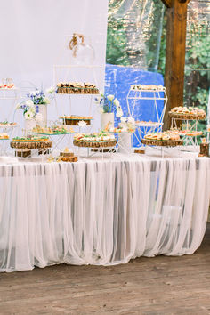 a table topped with lots of desserts on top of a white table cloth covered table