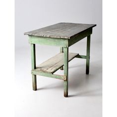 an old wooden table sitting on top of a white floor next to a small shelf