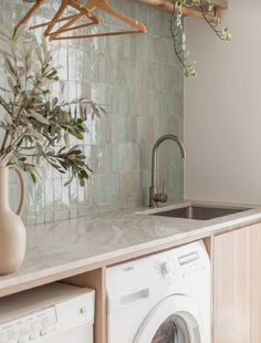 a washer and dryer in a kitchen with green tiles on the wall behind it