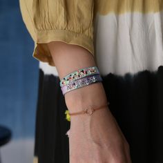 a woman wearing two bracelets with flowers on it's wrist and holding onto her hand