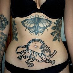 a woman with tattoos on her stomach has a tiger and butterfly tattoo on her belly