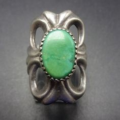 "VINTAGE NAVAJO RING DESCRIPTION: This classic sand cast ring features a gorgeous specimen of natural green turquoise. The gemstone is secure in sawtooth bezel, on a foundation of heavy gauge vintage sterling silver. This ring will be a treasured addition to your collection of fine vintage Native American jewelry. MEASUREMENTS: Ring face measures 1 1/8\" north to south Cabochon measures 13mm x 8mm RING SIZE: 5 3/4 WEIGHT: 10.5 grams SIGNED: no STERLING: unmarked, verified sterling silver" Southwestern Green Turquoise Ring With Large Stone, Southwestern Style Green Turquoise Ring With Large Stone, Southwestern Green Cabochon Rings, Vintage Green Jewelry With Large Stone, Southwestern Style Collectible Turquoise Ring, Unique Green Polished Turquoise Ring, Southwestern Style Green Turquoise Collectible Ring, Unique Green Turquoise Ring With Polished Finish, Classic Green Jewelry With Large Stone