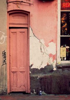 an old building with graffiti on it and a red door in the doorway that says real estate