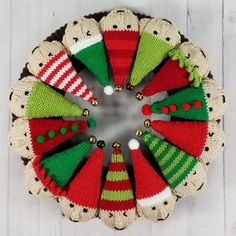 knitted christmas ornaments arranged in a circle on top of a wooden table with white boards