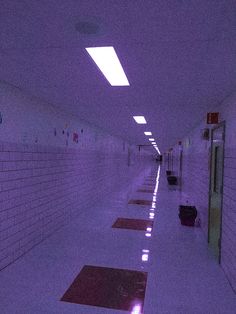 an empty hallway with white walls and purple lighting