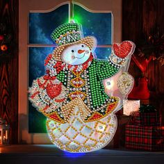 a lighted snowman sitting in front of a window