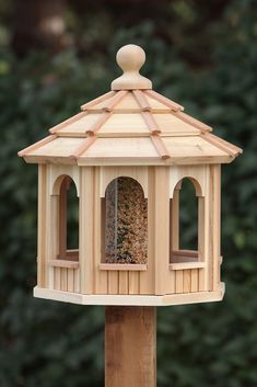 a wooden bird feeder on top of a wooden post