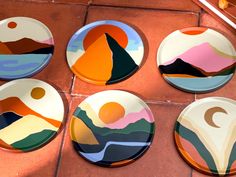 four plates with different designs on them sitting on a tile floor