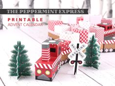 the paper mini express printable train is next to small christmas trees and a railroad crossing sign