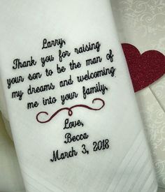 a white towel with embroidered words on it and a red heart in the corner next to it