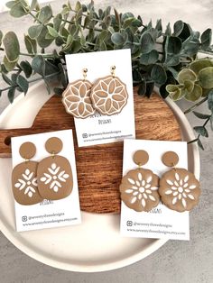 three pairs of brown and white earrings on a plate