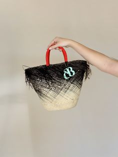 The Playa bag is an elegant basket handwoven out of the finest toquilla straw. It is made by hand in the coasts of Ecuador using a technique that is part of the UNESCO Intangible Cultural Heritage list. The ombre-dyed tote features a frayed edge, contrasting handles, and the signature Cuckoo B monogram in lacquered ethically-sourced buffalo horn, which is handmade in Vietnam. Black Woven Beach Bag Made Of Natural Fiber, Black Straw Bag For Market, Black Straw Bag With Bamboo Handle For Summer, Black Handwoven Natural Fiber Beach Bag, Handmade Black Beach Bag With Natural Fiber, Black Handwoven Bucket Bag For Vacation, Black Basket Beach Bag In Natural Fiber, Black Handwoven Bucket Straw Bag, Handwoven Black Bucket Bag For Vacation