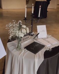 the table is set up with flowers and cards for guests to write in their place settings