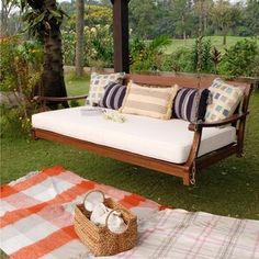 a wooden swing bed sitting on top of a lush green field