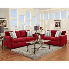 a living room with red couches and white rugs on the wooden flooring