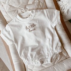 Comfort meets style with our oversized embroidered 'Little Love' Romper. Made from breathable & soft unlined cotton fabric, it is the perfect gender neutral piece for your little love. Featuring snap buttons on the neck for easy changing. Available in sizes NB-2Y.  Milk with Bronze Embroidery Made from 100% Cotton. Care Instructions Cold Gentle Machine Wash. Do Not Soak Or Bleach. Dry Flat In Shade. Do Not Tumble Dry. Custom Embroidery Loungewear Tops, Custom Embroidered Relaxed Fit Tops For Loungewear, Relaxed Fit Tops With Custom Embroidery For Loungewear, White Custom Embroidered Tops For Loungewear, Basic Embroidered Cotton Tops, Cotton Tops With Letter Embroidery For Loungewear, Cotton Tops With Embroidered Graphics For Loungewear, Cotton Tops With Embroidered Logo For Loungewear, Basic Cotton Tops With Letter Embroidery