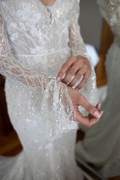 a woman in a white wedding dress holding her hands together