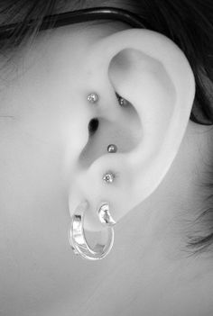 a woman's ear with three piercings on it