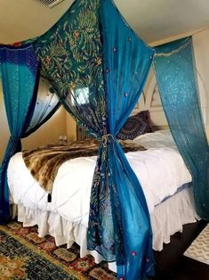 a canopy bed with blue drapes on it's headboard and foot board