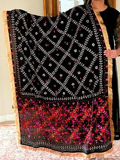 This traditional black silk phulkari gotta patti work dupatta is meticulously crafted with luxurious pure Chinon silk, featuring all over Gotta Patti hand embroidery and boasts a striking metallic gold trim along the border. This classic piece is perfect for celebrations such as weddings, sangeet, jaago, and chunni ceremonies. Effortlessly pair this dupatta with any color for an elegant contrast and make it an admirable present for birthdays or anniversaries. Material: Pure silk chinonWork: Silk Black Traditional Wear With Mirror Work For Navratri, Black Semi-stitched Bohemian Saree, Black Chanderi Traditional Wear With Mirror Work, Black Dupatta With Motifs For Navratri, Black Chanderi Saree With Mirror Work, Navratri Black Dupatta With Motifs, Black Silk Traditional Wear With Mirror Work, Black Bohemian Traditional Wear In Chanderi, Black Bohemian Chanderi Saree