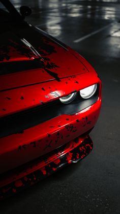 the front end of a red sports car with black paint splattered on it