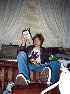 a man sitting on a couch holding up a book