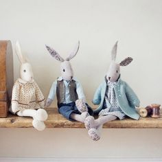 three stuffed rabbits sitting on top of a shelf next to a clock and other items