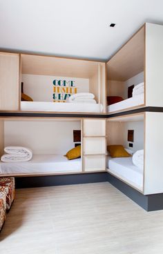 three bunk beds in a room with white sheets and yellow pillows on the bottom shelf