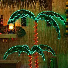 lighted palm trees are displayed in front of a wall with lights and decorations on it