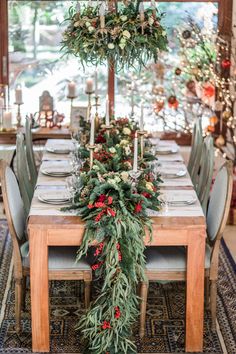 a dining room table decorated with greenery and red berries is surrounded by holiday decorations