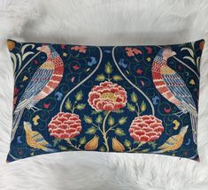 a blue pillow with two birds and flowers on it