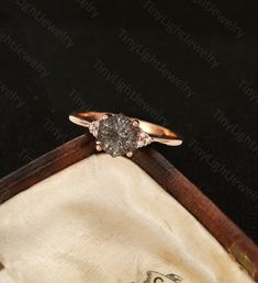 an engagement ring with two diamonds in it on top of a velvet box that is open