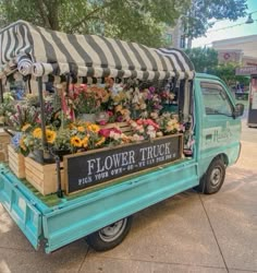 a flower truck is parked on the side of the road with flowers and plants in it