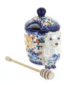 a ceramic cookie jar with a wooden spoon in it and a bear design on the lid