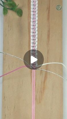 a piece of wood that has some string attached to it with pink and white beads