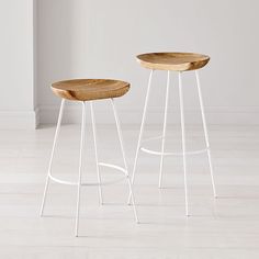 two wooden stools sitting on top of a white floor