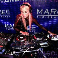 a woman with headphones on mixing music in front of a large screen at marquee nightclub