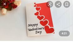 a valentine's day card next to a bouquet of roses on a white surface