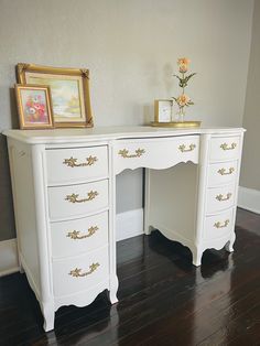 a white desk with gold trimmings on top and drawers in front of it